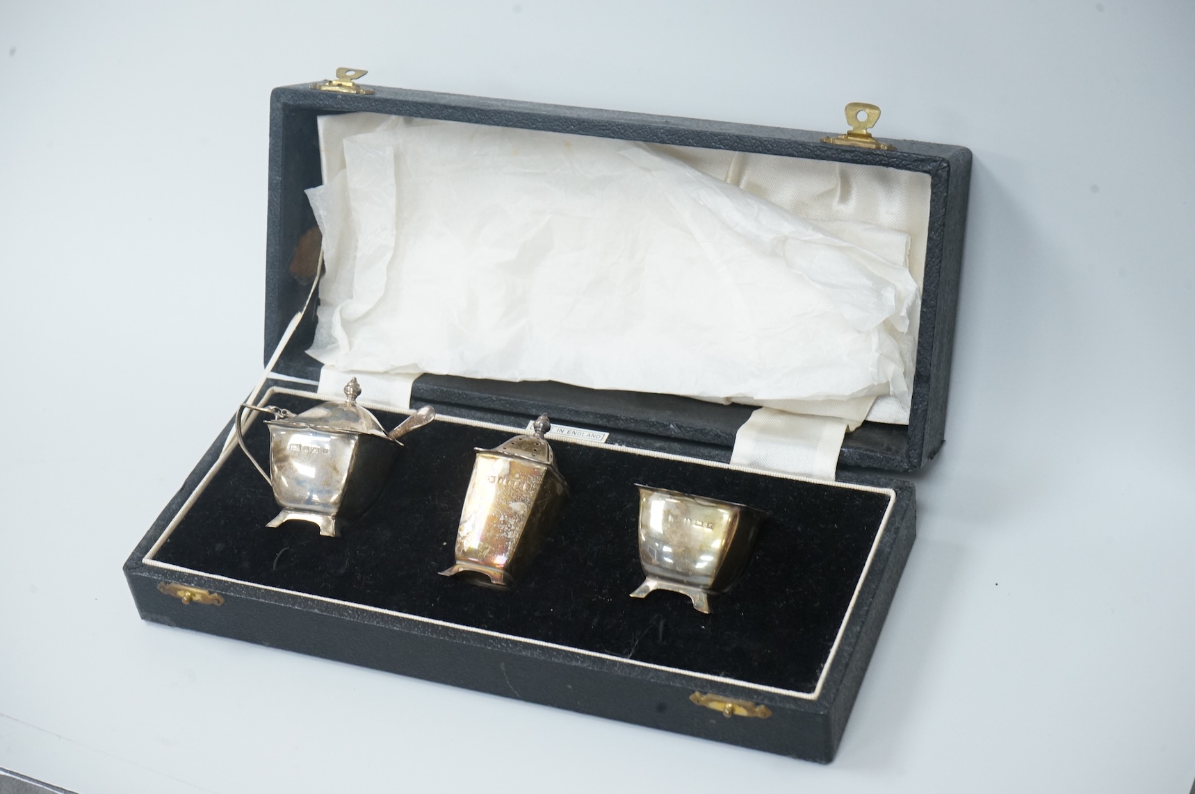 A pair of cased Elizabeth II silver three piece condiment sets, by William Adams Ltd, Birmingham, 1955, one spoon missing.